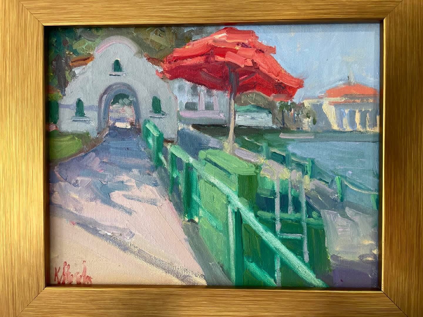 Plein air painting of a red umbrella beside a white archway building near the harbor